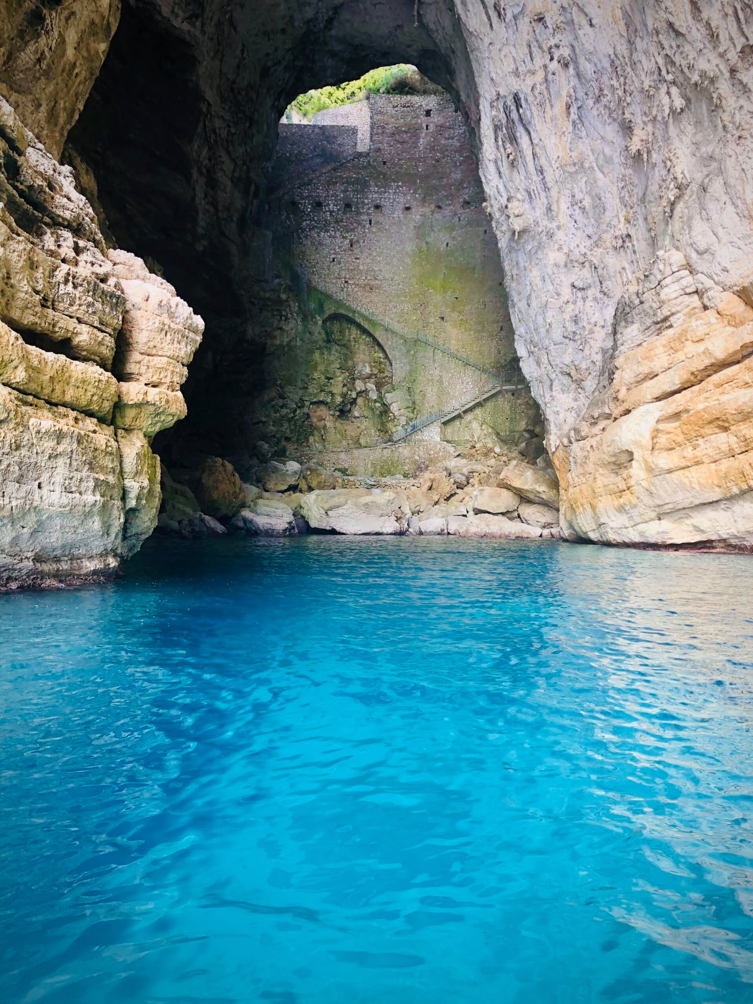 L'interno della Grotta del Turco visto dal mare, con l'acqua azzurra e la scalinata sulla parete di roccia